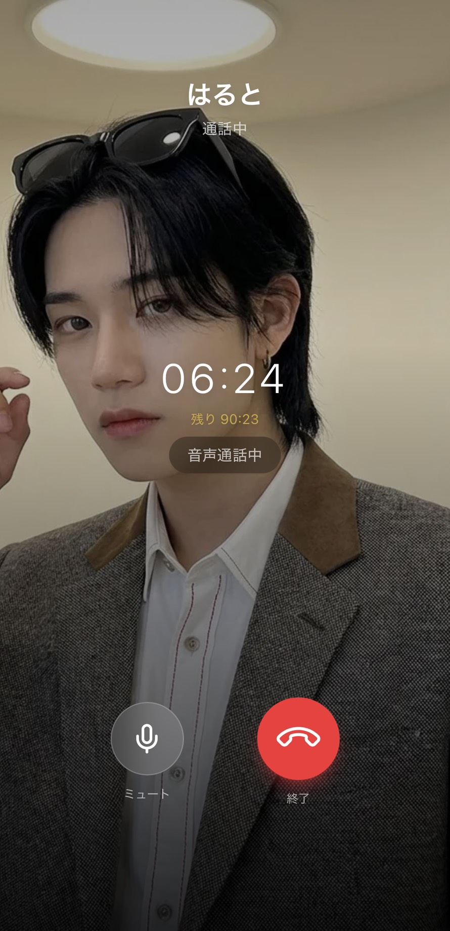Aimaの男性キャラ「はると」との音声通話画面のスクリーンショット。「通話中」表示、経過時間「06:24」と残り時間「90:23」、マイク・ミュート・終了ボタン、キャラの全身ビジュアルが映った没入感のある画面。テキストでは伝わらない声のニュアンスが流れ込んでくる、有料プランの主役機能を視覚的に証明する場面